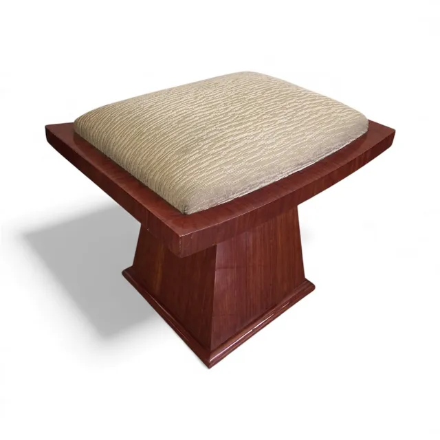 Tabouret avec coussin clair et base en bois poli.