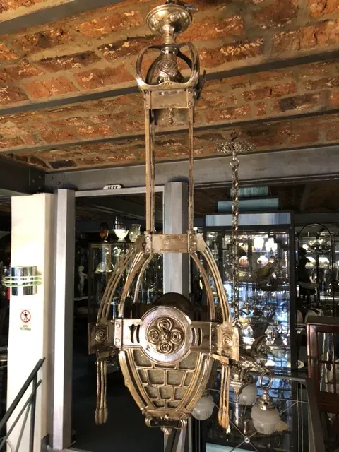 Antique hanging lamp in Mackintosh style, elegant and decorative, hanging from a brick ceiling.