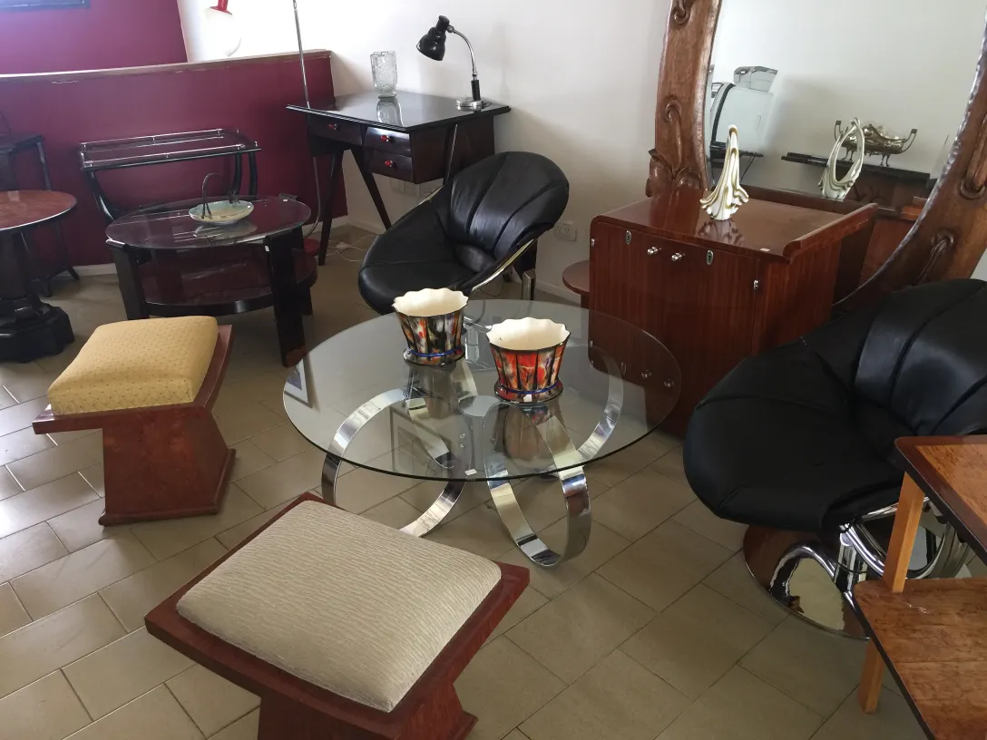 Banqueta moderna com assento acolchoado e design elegante, ao lado de poltronas.