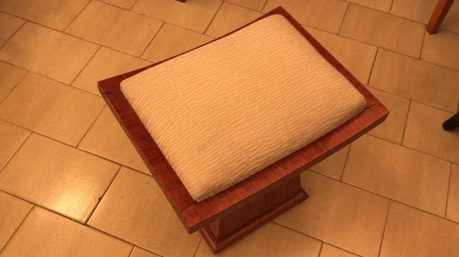 Sgabello antico con cuscino chiaro, elegante e comodo.