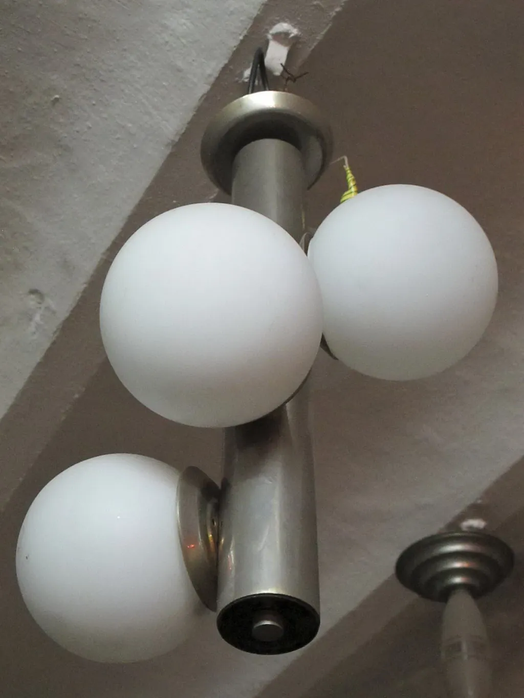 Antique hanging lamp with three white balls, cozy atmosphere.