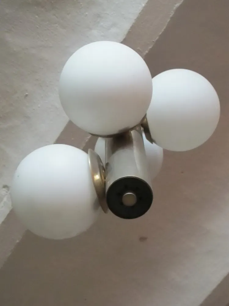 Antike Hängelampe mit weißen Glaskugeln, neutraler Hintergrund.