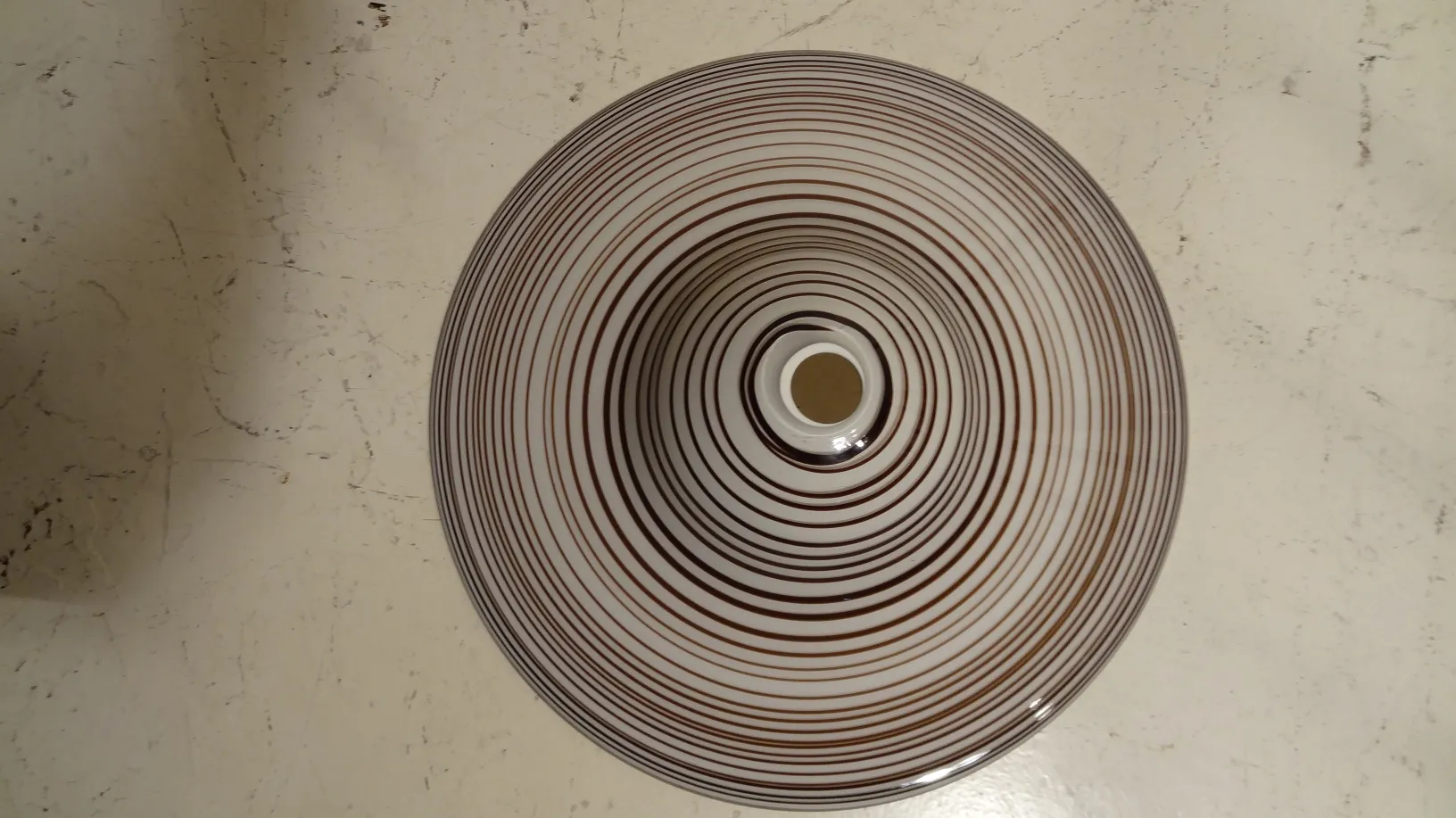 Lámpara de techo antigua con patrones en espiral sobre fondo claro, ideal para decoración.