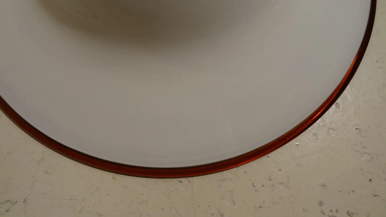 Lampada a sospensione antica con dettagli arrotondati in un ambiente semplice.