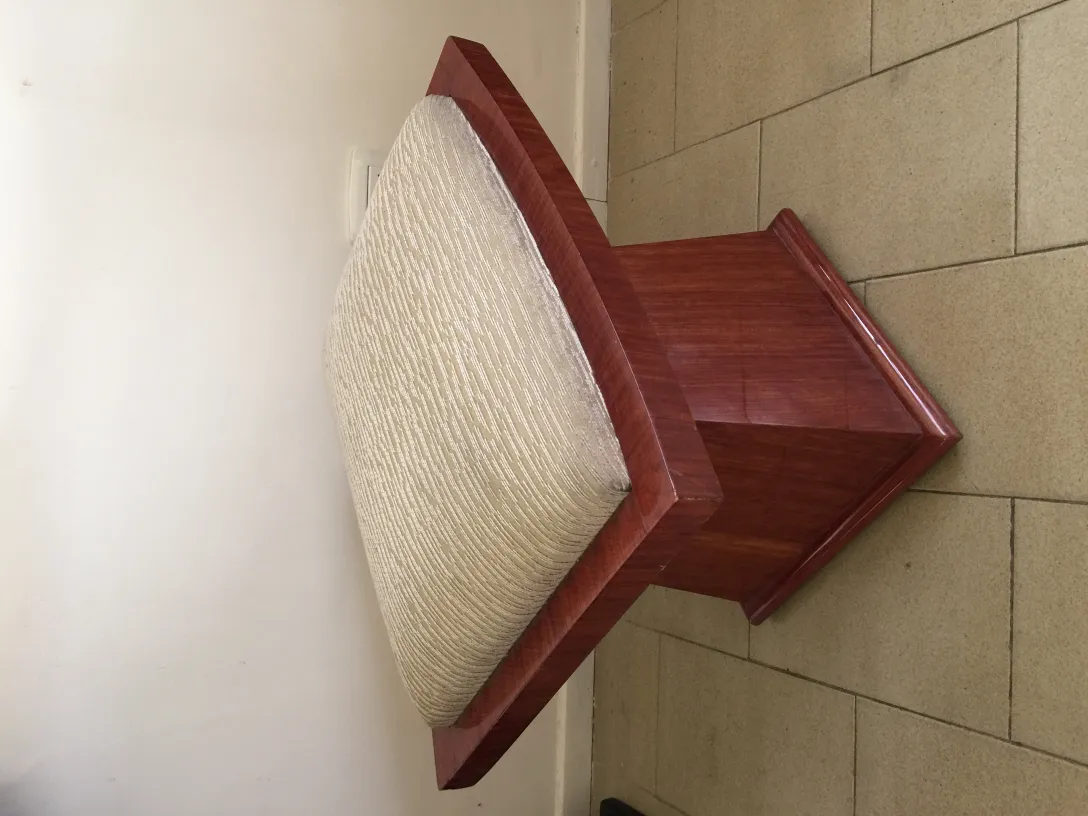 Banqueta antigua con un asiento cómodo de color claro, en un ambiente neutro.