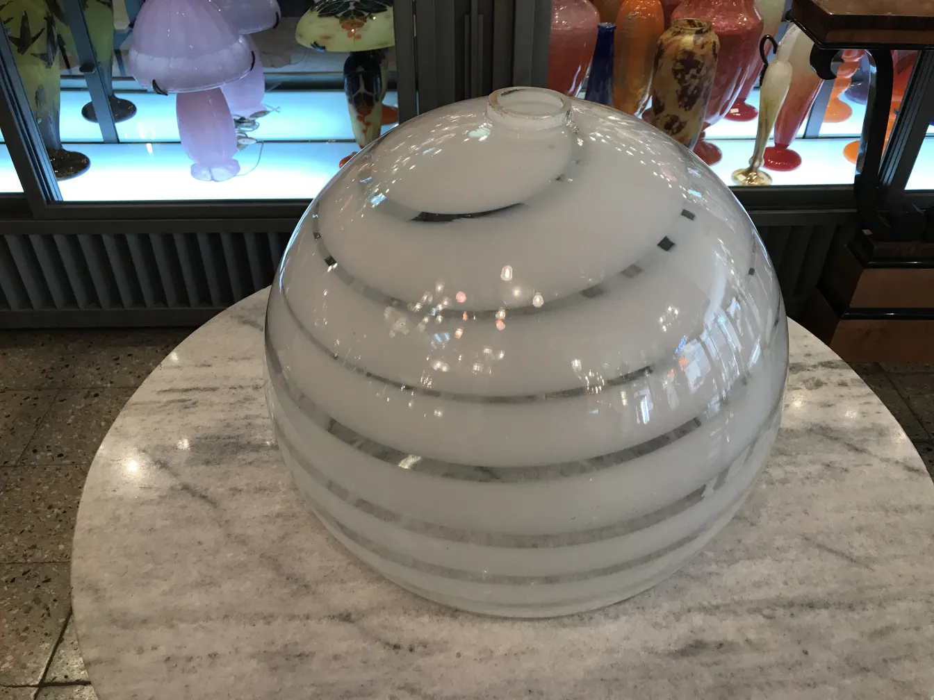 Antigua lámpara de techo esférica blanca con líneas suaves, decorativa.