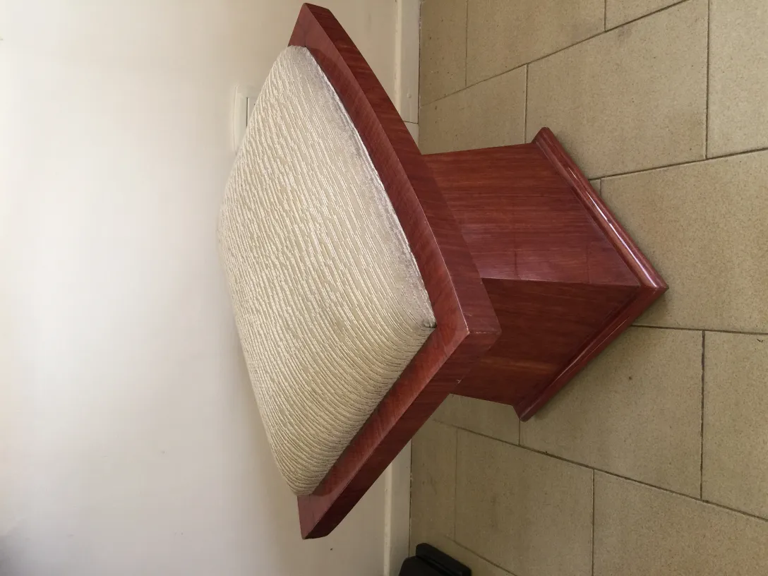 Banqueta antigua con perímetro de madera y asiento acolchado en tonos claros.