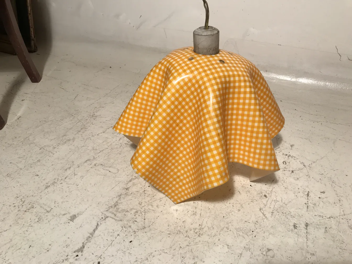 Lâmpada de teto antiga com sombrinha amarela xadrez em um ambiente vintage.