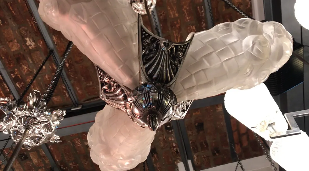 Lampada a sospensione antica Degue con design elegante e dettagli decorativi, sfondo di mattoni a vista.