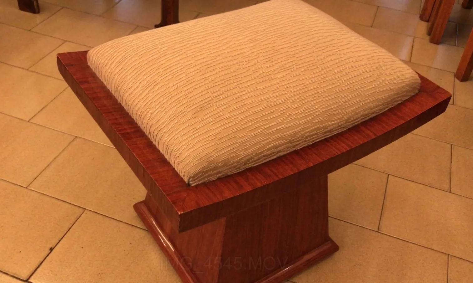 Banqueta antiga com assento confortável de cor clara, ideal para decoração