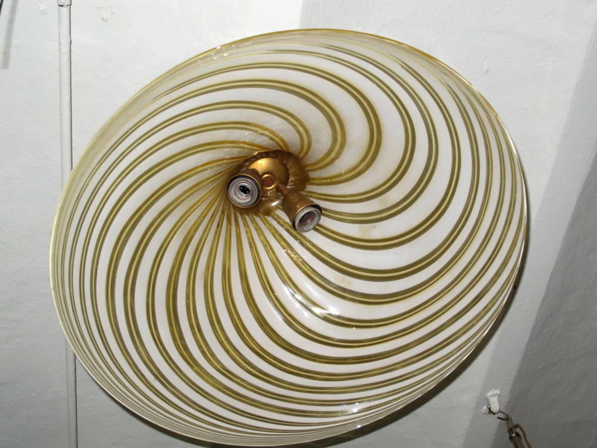 Antica lampada a sospensione con design spiralato e colore dorato, ideale per arricchire gli spazi.