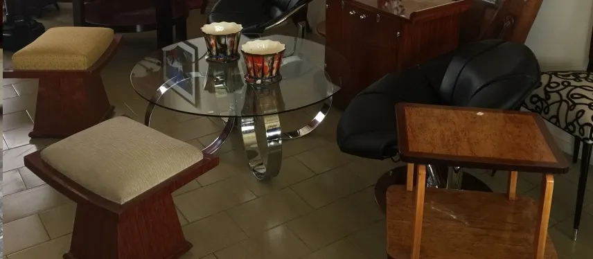 Duas banquetas antigas ao lado de uma mesa de vidro.