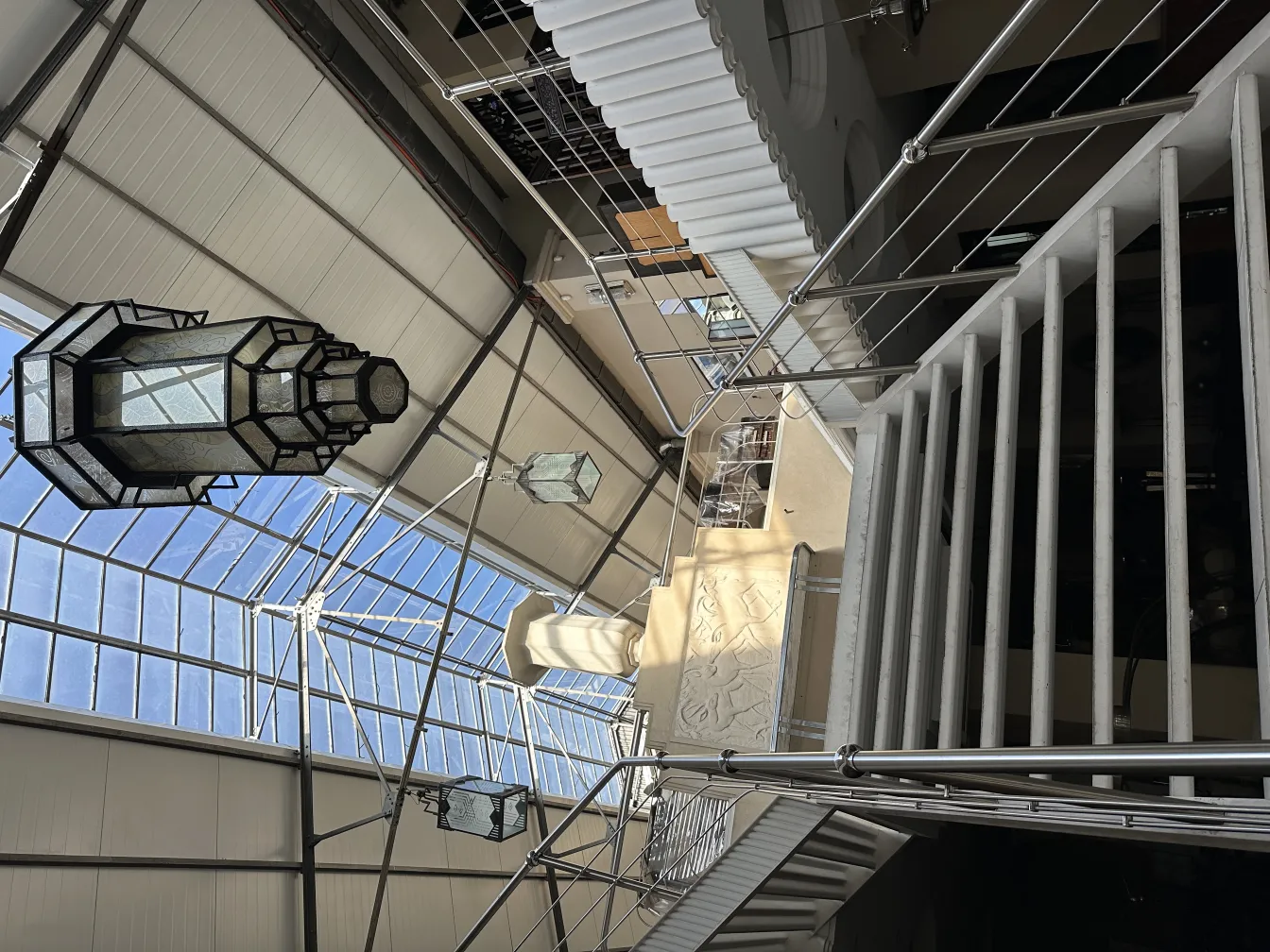 عرض فانوس قديم معلق من الزجاج في ممر مضاء.