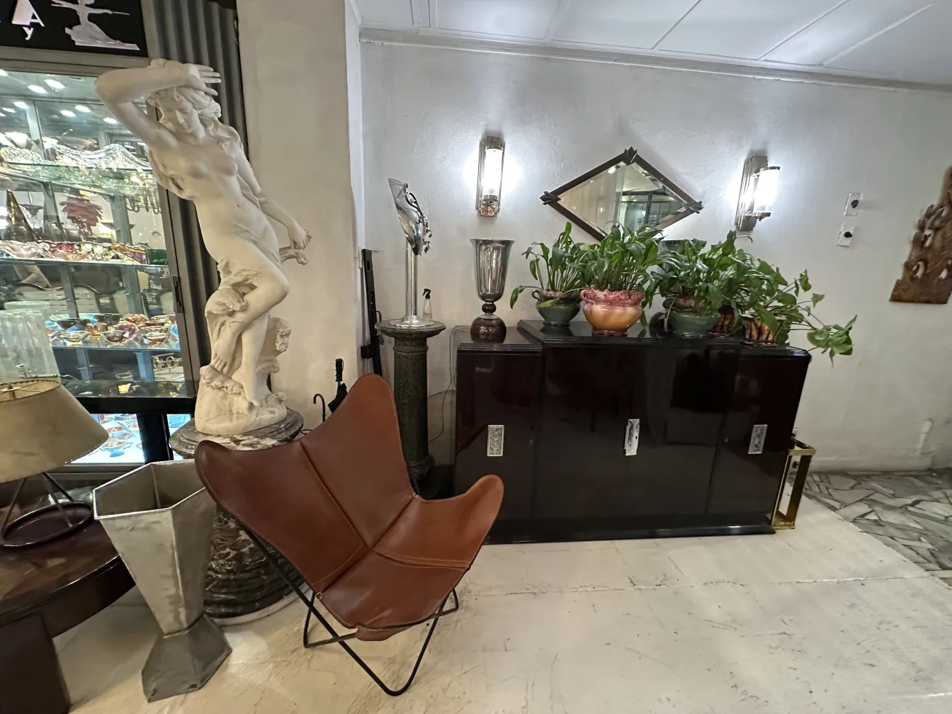 Antiker Sessel in einem eleganten Setting mit Statuen und Pflanzen.