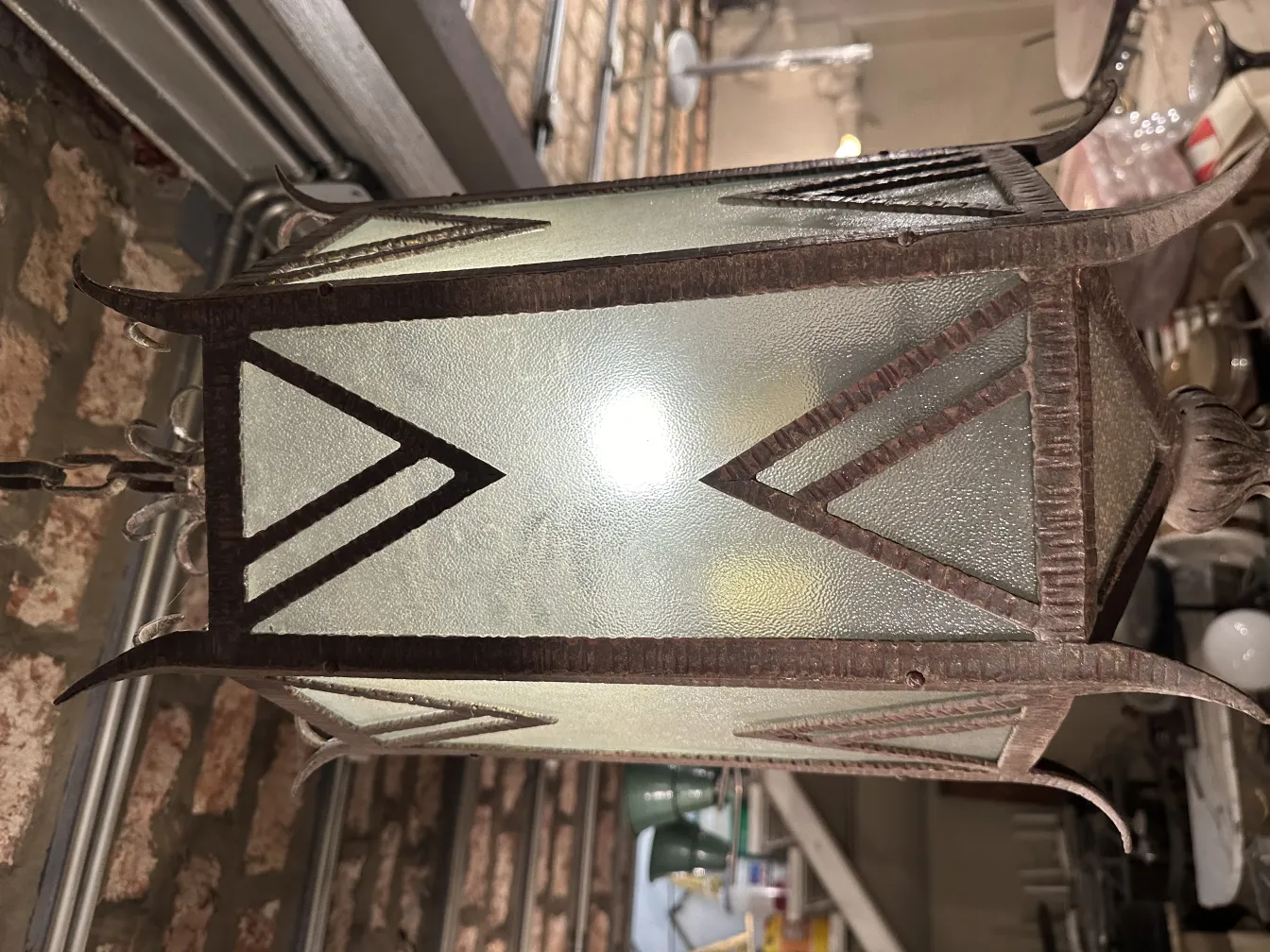 Lanterna antica in vetro con design geometrico e luce brillante.