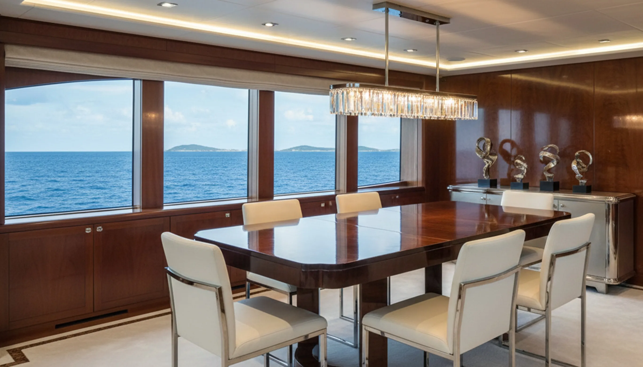 Table à manger antique pour 8 personnes dans un espace élégant avec vue sur la mer.