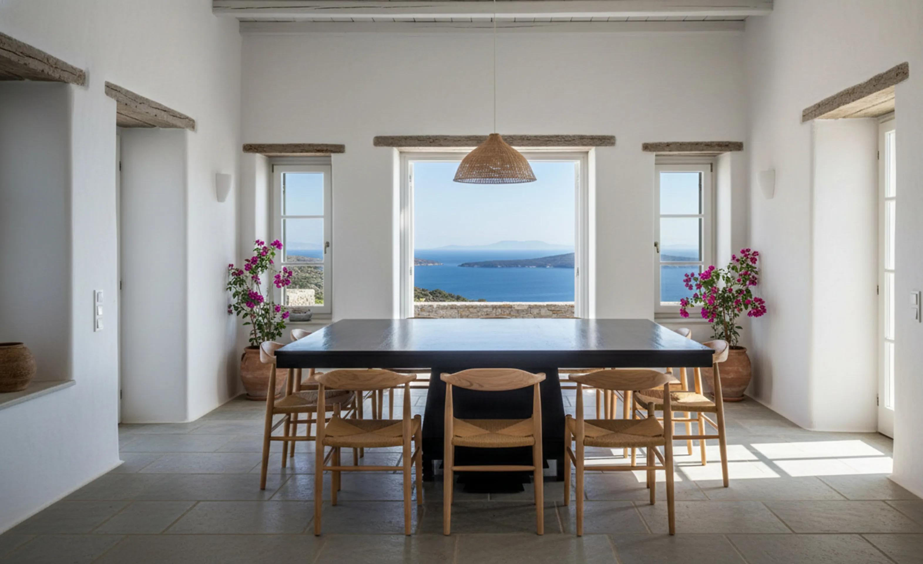 Tavolo da pranzo antico per 8 persone, circondato da sedie in uno spazio luminoso con vista sul mare.
