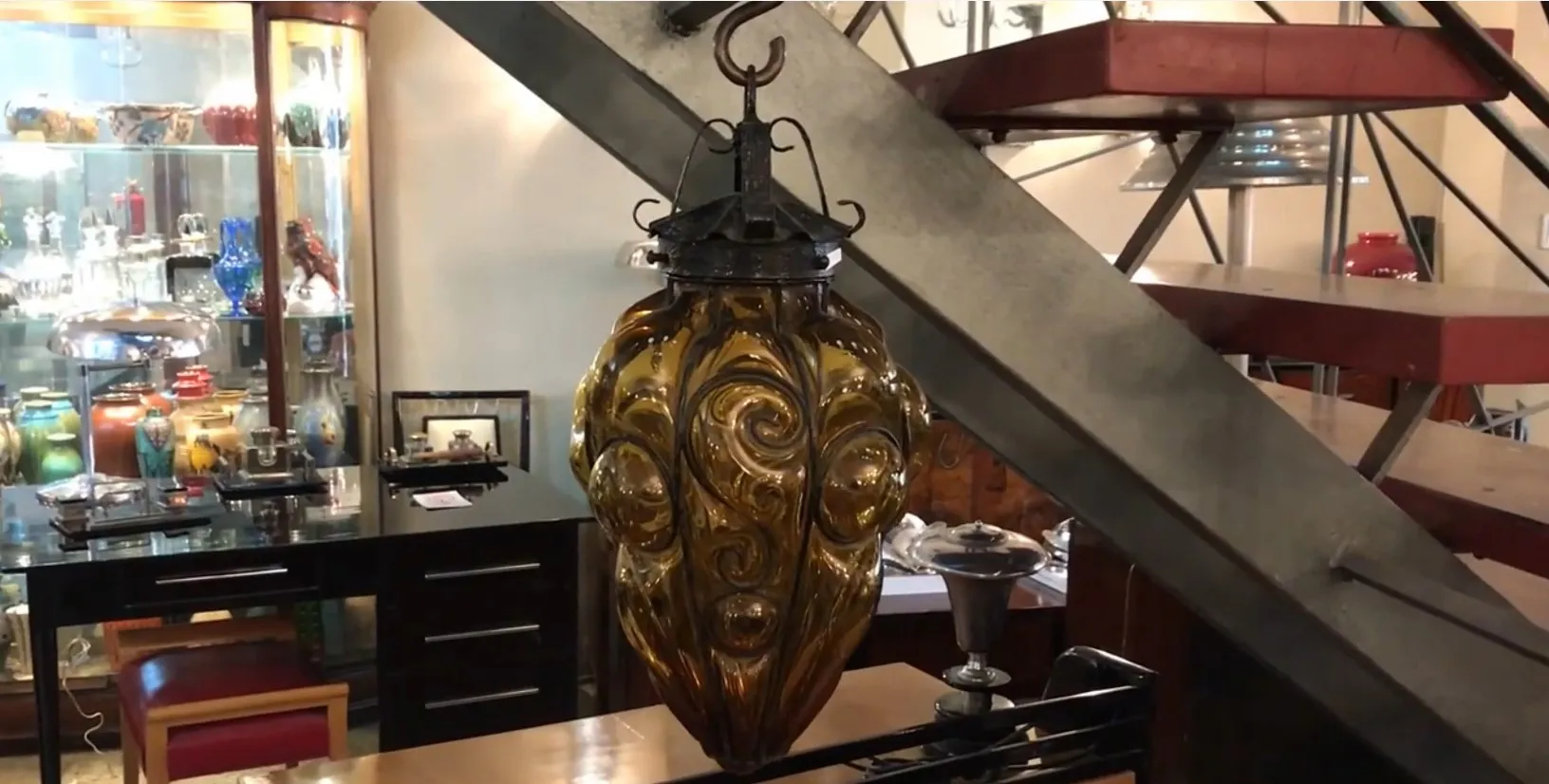 Lanterna antica in vetro marrone con dettagli decorativi, appesa.