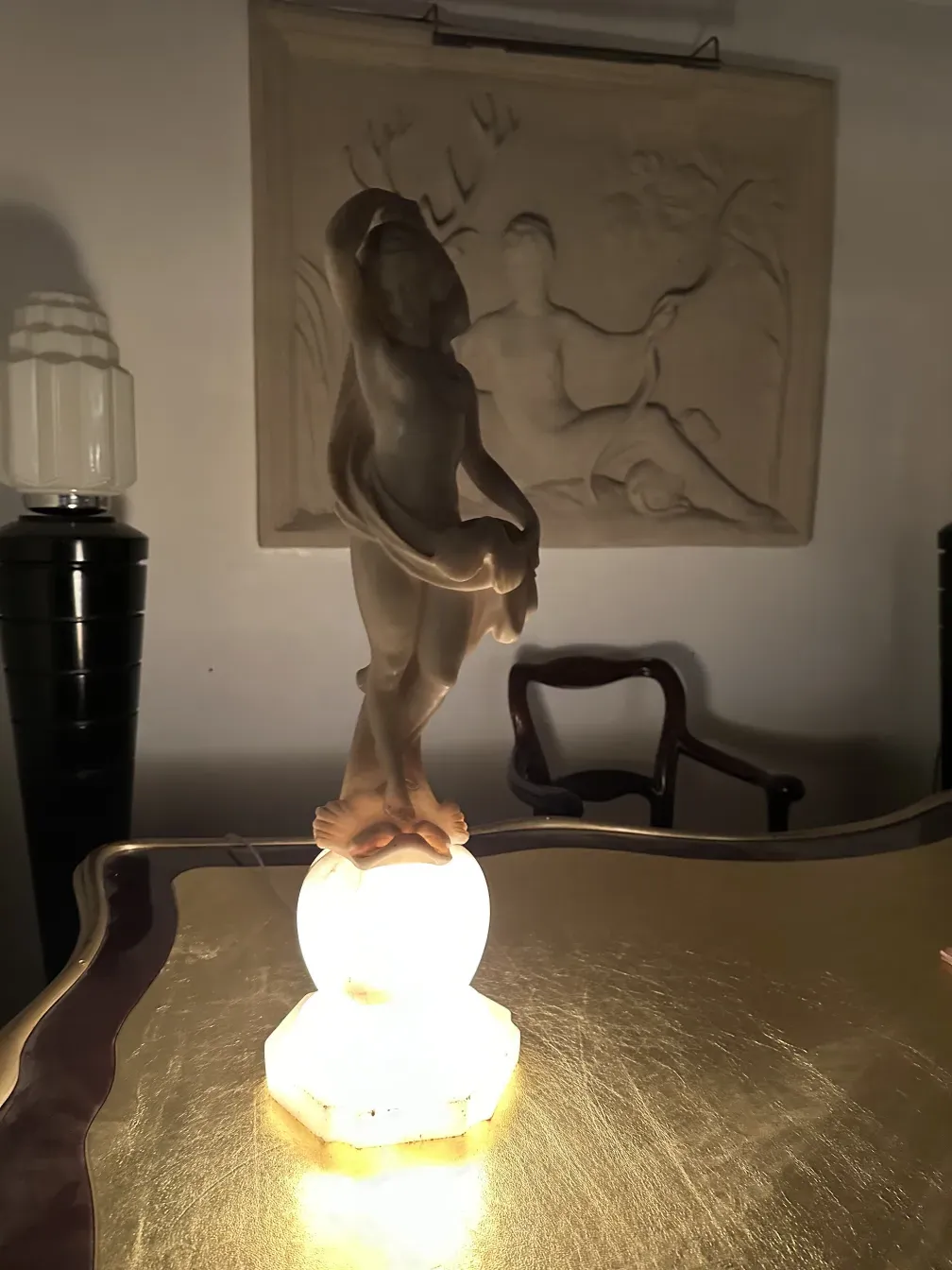 Scultura antica di figura umana con sfondo decorativo