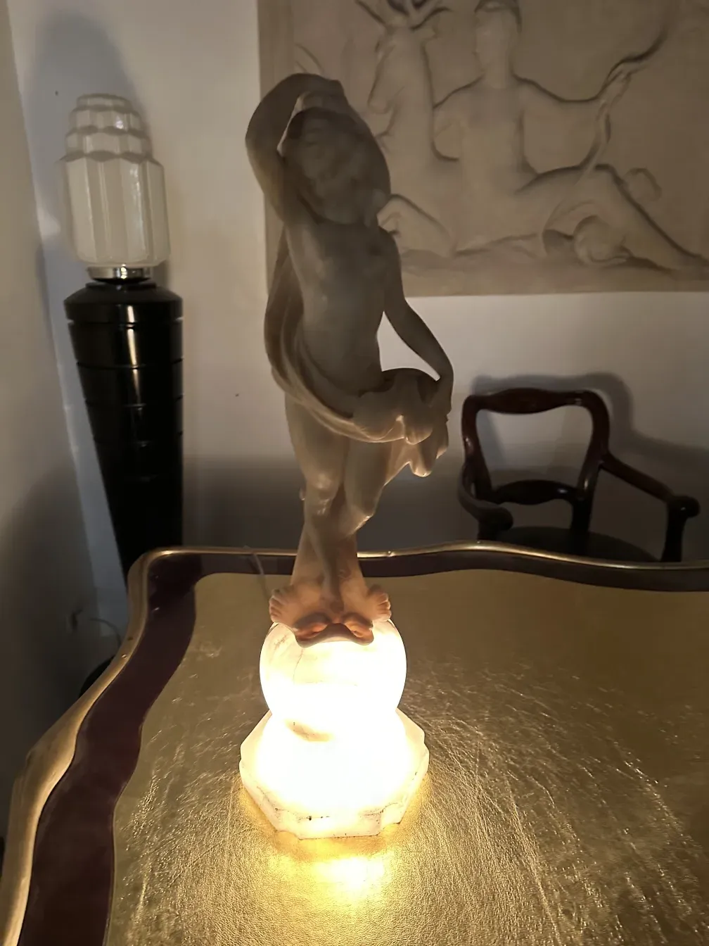 scultura antica di figura umana con dettagli chiari, in un ambiente caldo