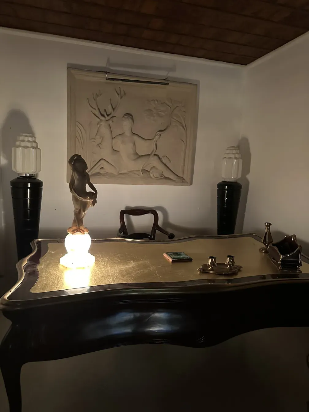 Scultura antica di figura umana illuminata in un ambiente elegante.