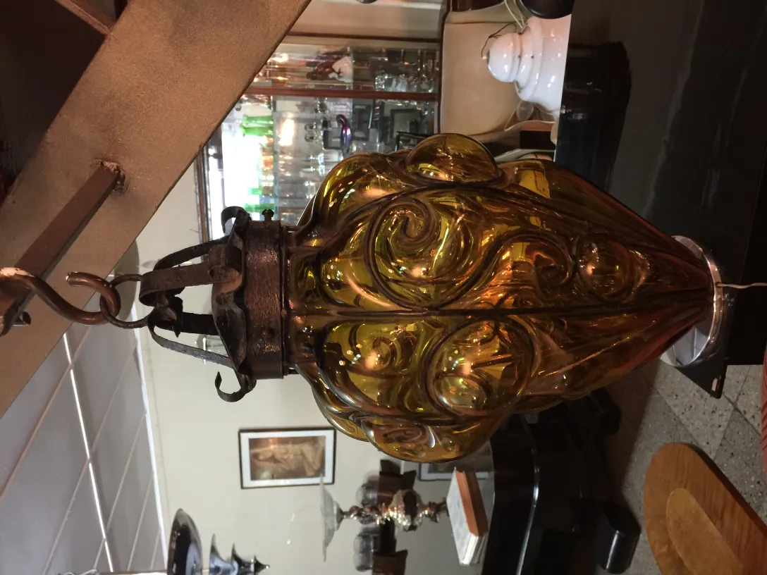 Antique yellow glass lantern with intricate design in a cozy setting.