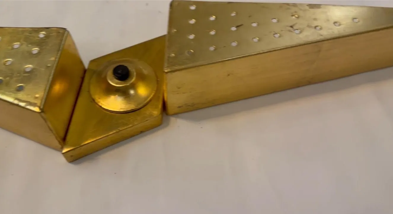 Arandela antiga com design triangular e perfurações douradas.