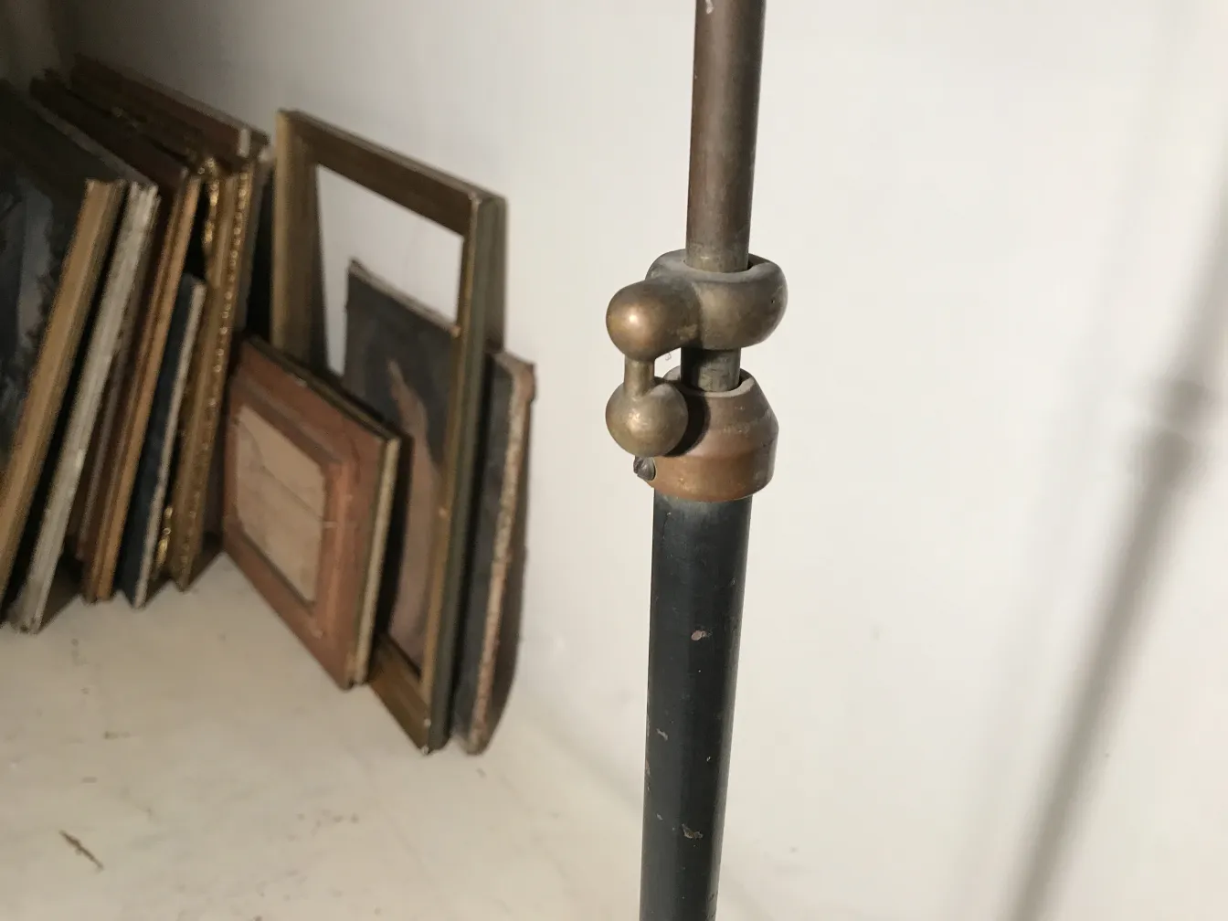 Antique floor lamp in Art Deco style with decorative features in a background of framed pictures.