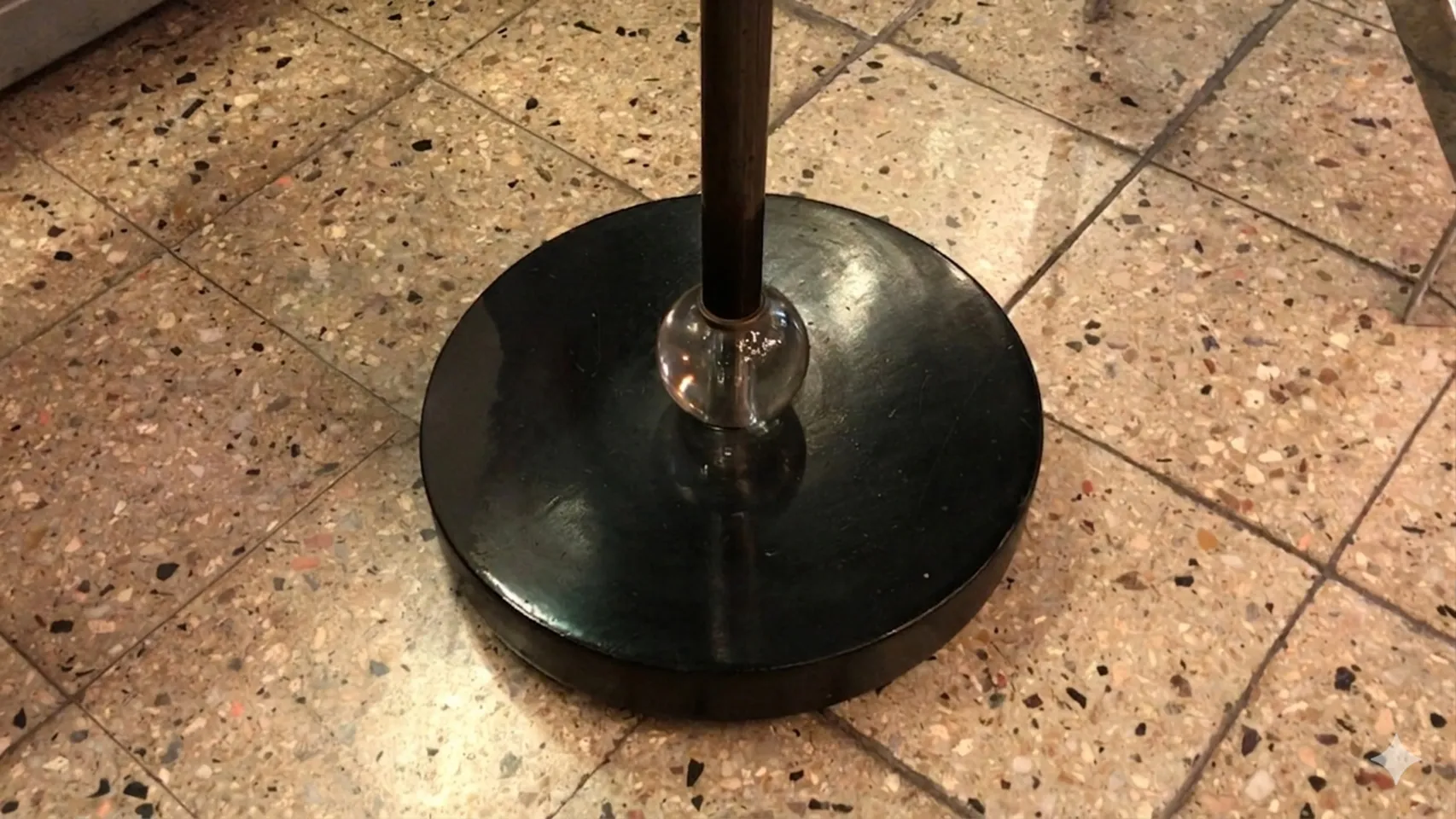 Luminária de pé antiga no estilo Art Deco com base preta e detalhes curvos em um ambiente elegante.