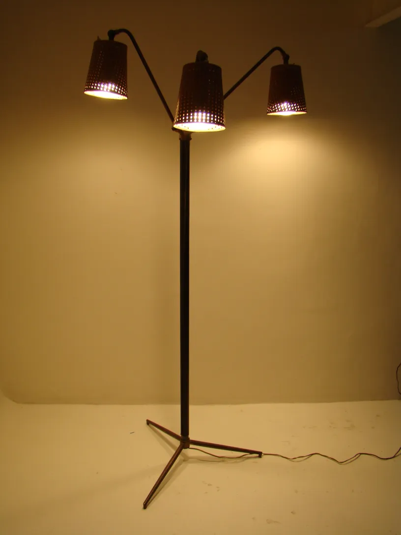 Ancienne lampe de sol avec trois lumières de style Art Deco, ambiance chaleureuse.