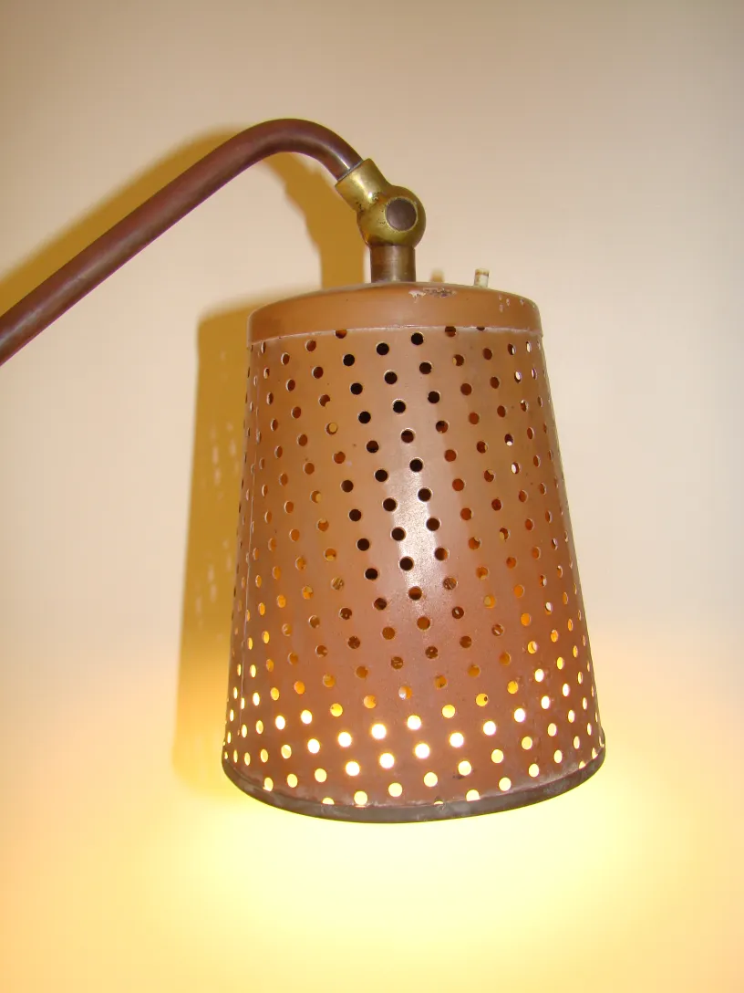 Antique floor lamp with perforated design, illuminating the room.