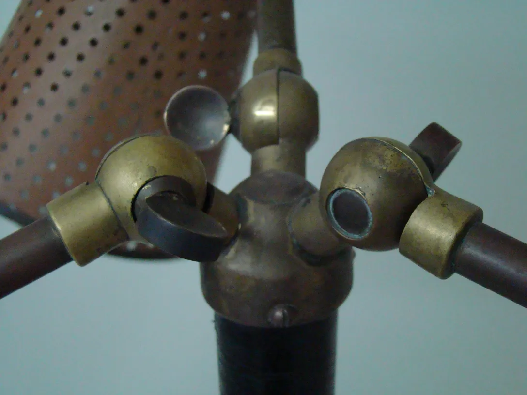 detalle de una lámpara de pie antigua de estilo art déco con acabados metálicos, fondo neutro.