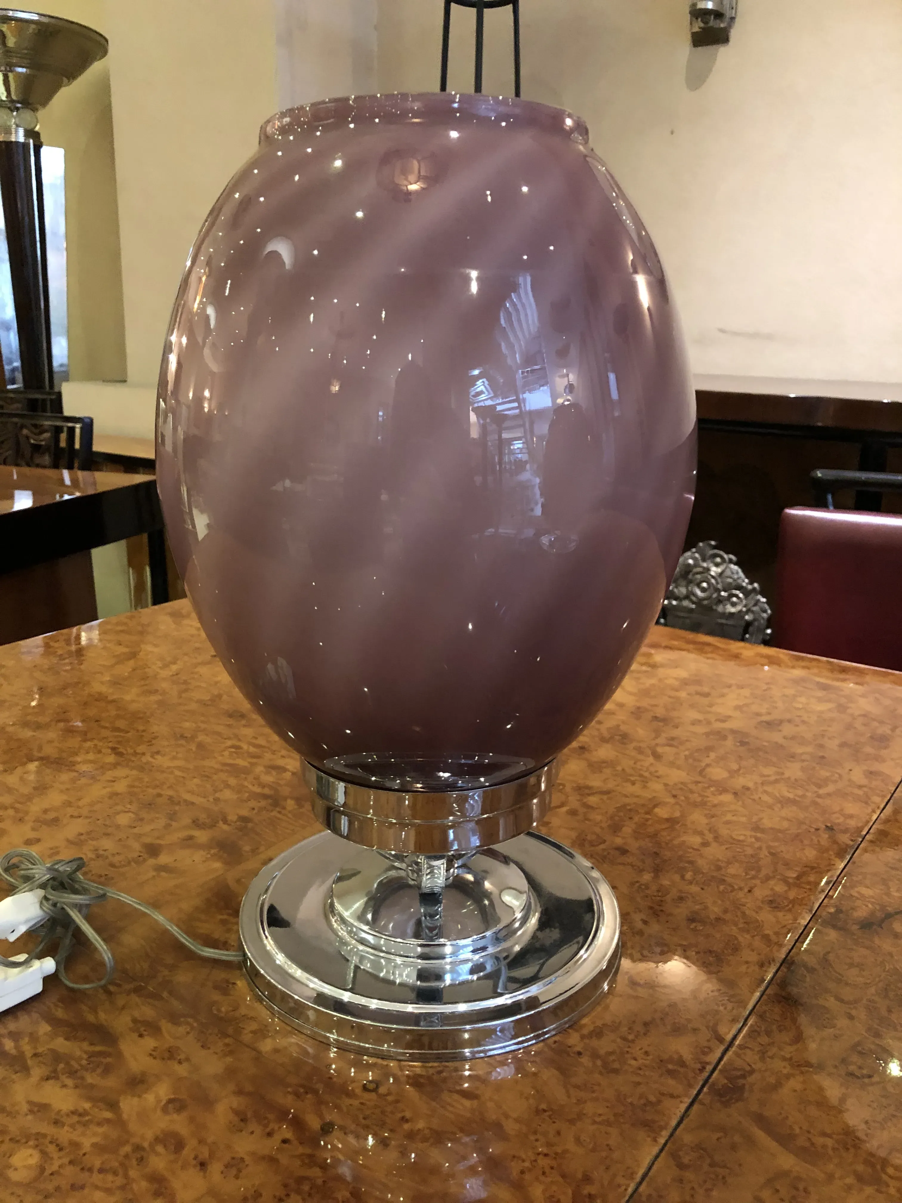 Dos lámparas de mesa antiguas con base brillante y pantalla rosa, decorando un ambiente cálido.