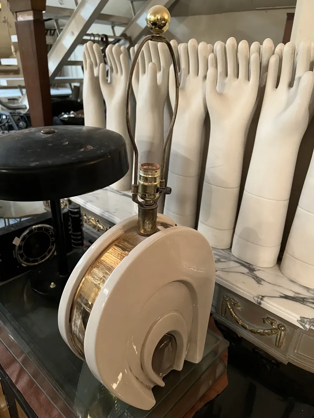 Lámpara de mesa antigua estilo Art Deco con base redonda y detalles dorados, rodeada de un ambiente vintage.