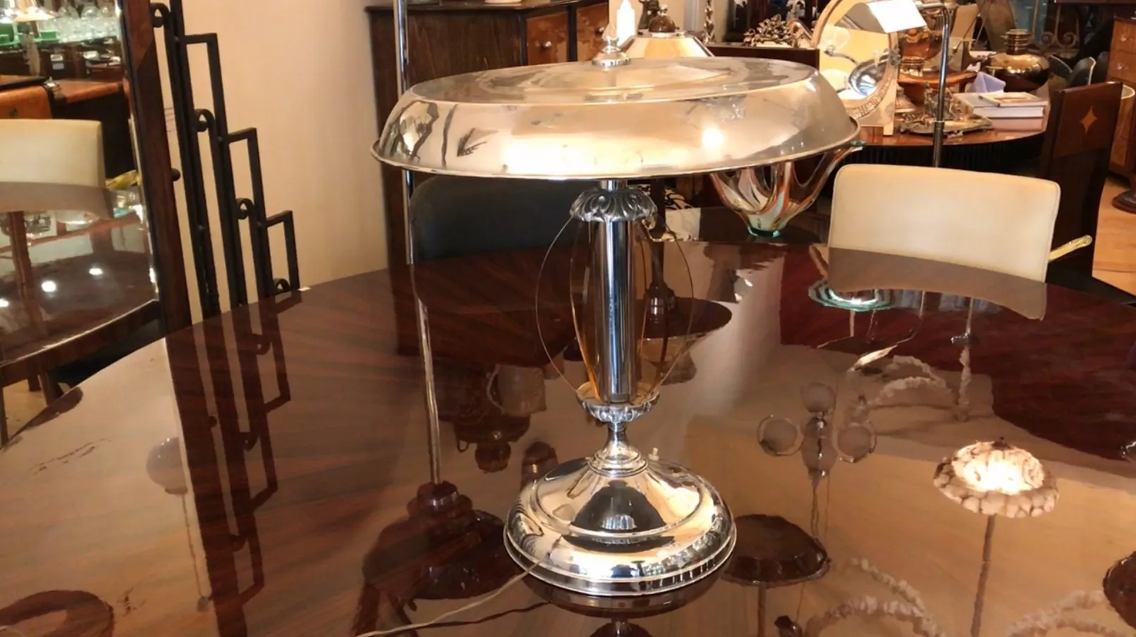 Antique table lamp in Art Deco style on a shiny table, surrounded by vintage furniture.