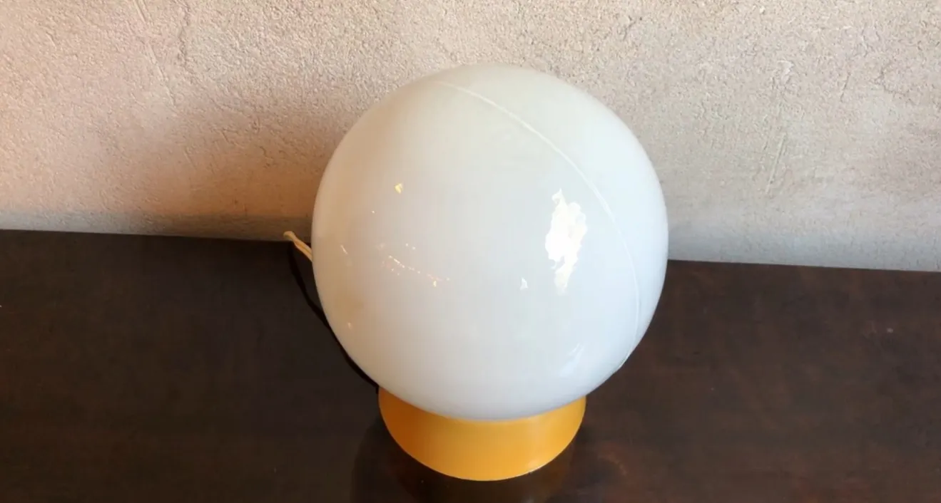 Lámpara de mesa antigua, con forma esférica, en un entorno cálido.
