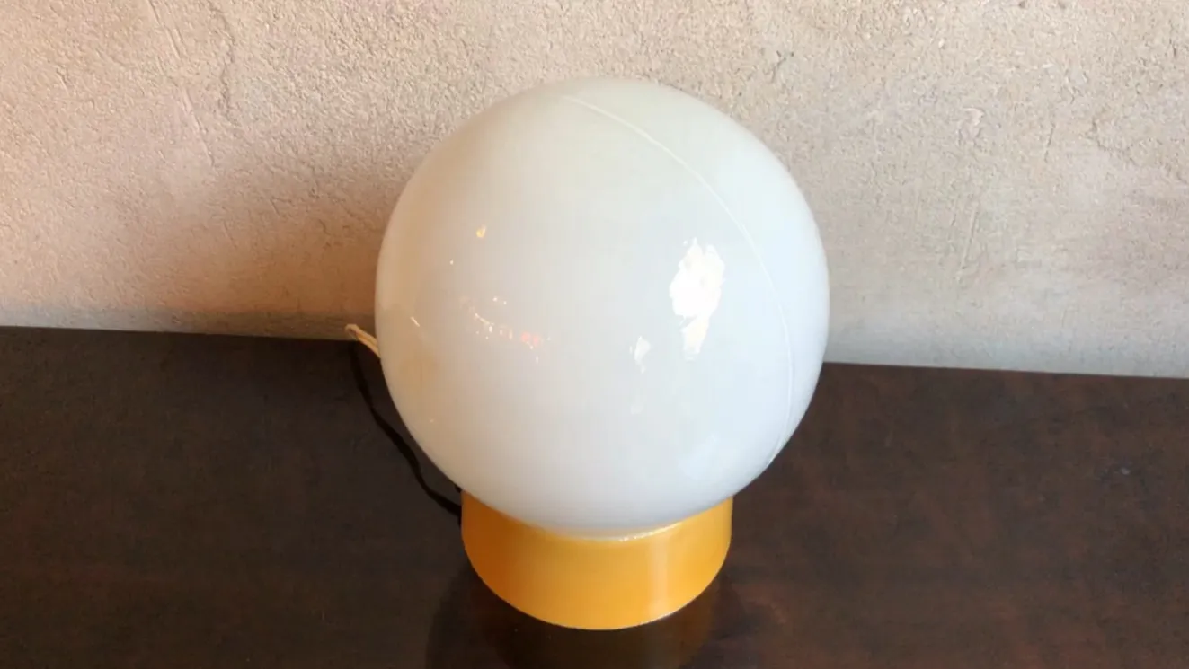 Lampada da tavolo antica sferica su un tavolo scuro, sfondo chiaro.