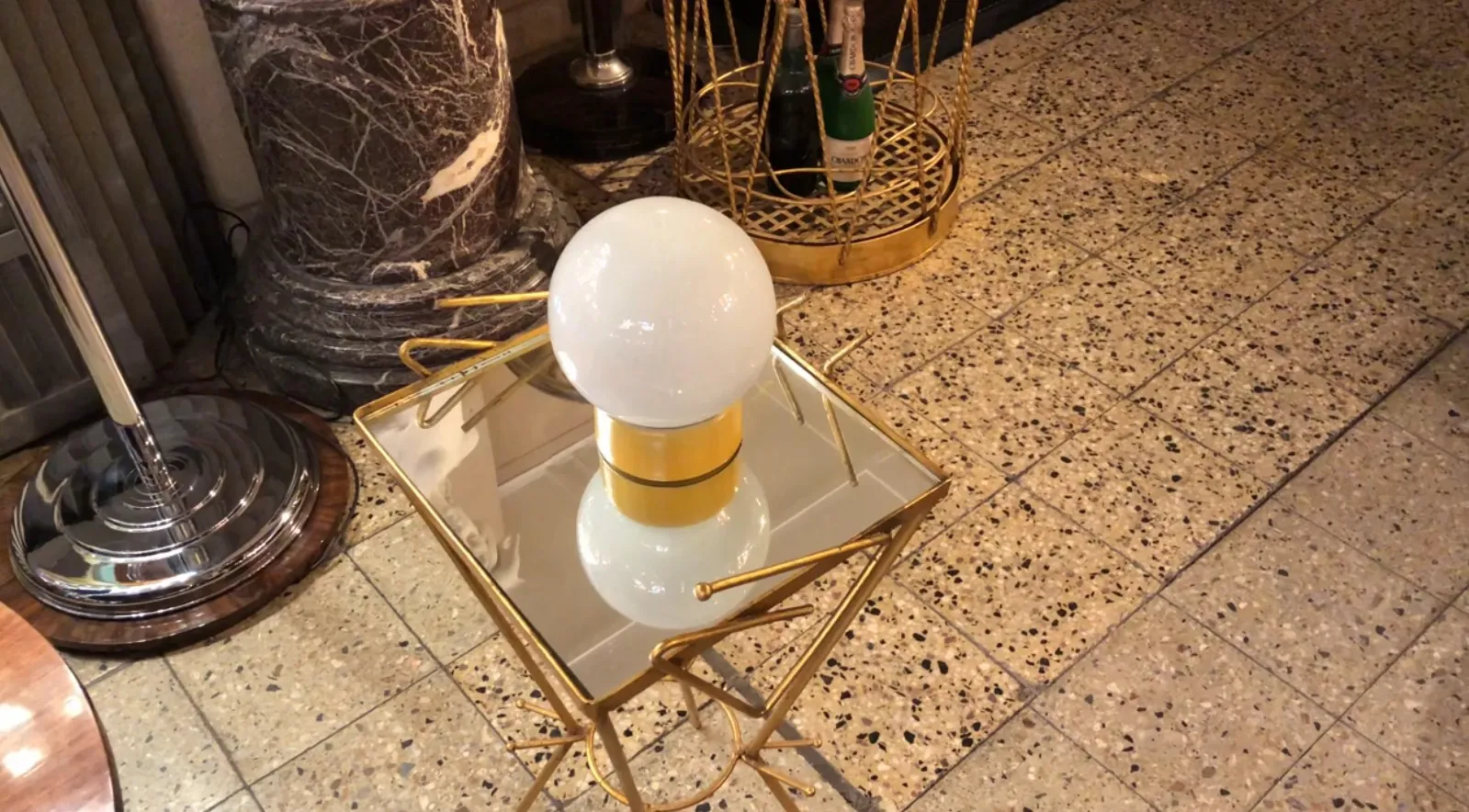 Luminária de mesa antiga com esfera branca sobre mesa espelhada, decoração elegante