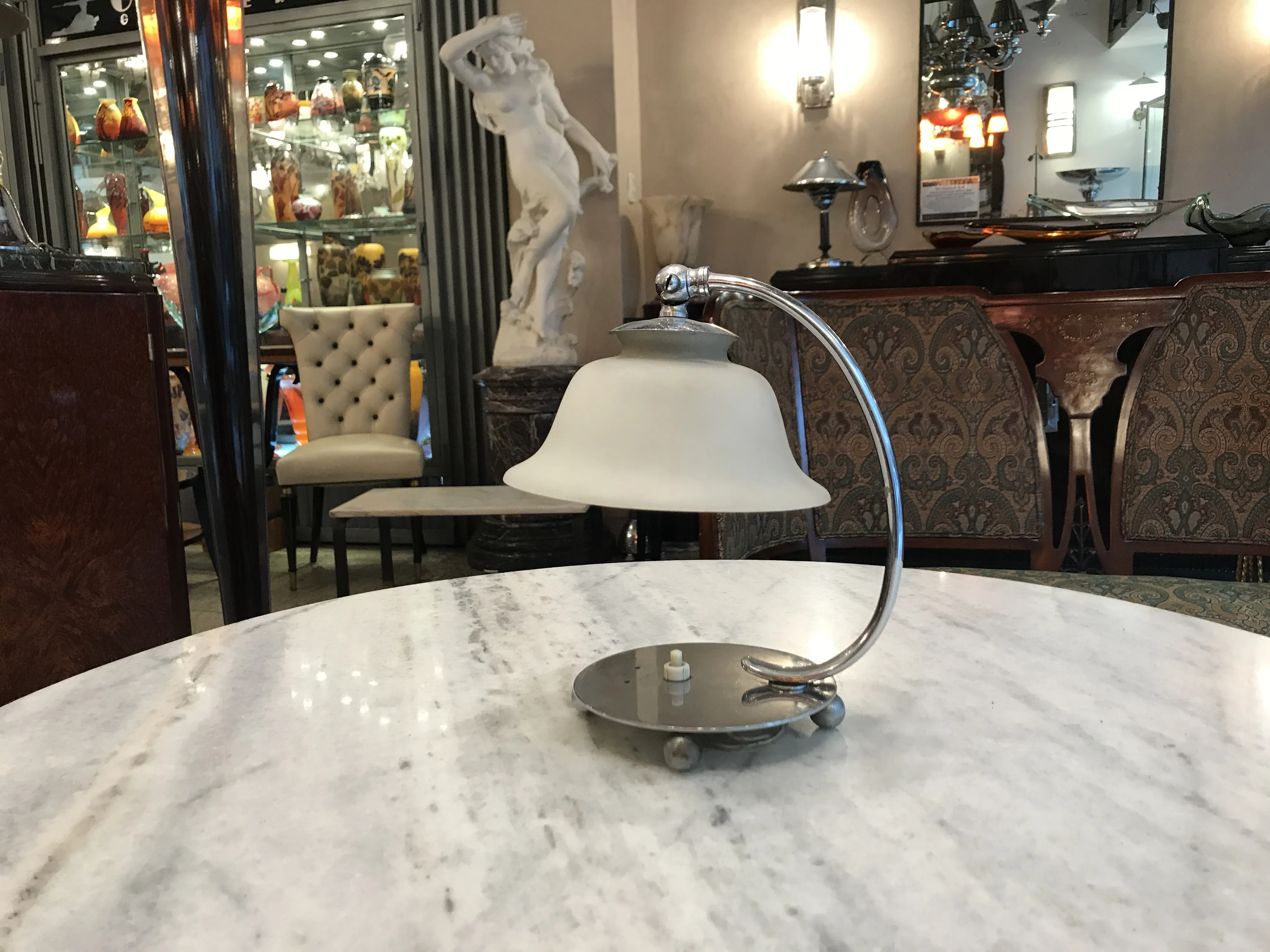 Antique table lamp with a metal base and bell-shaped shade in an antique environment.