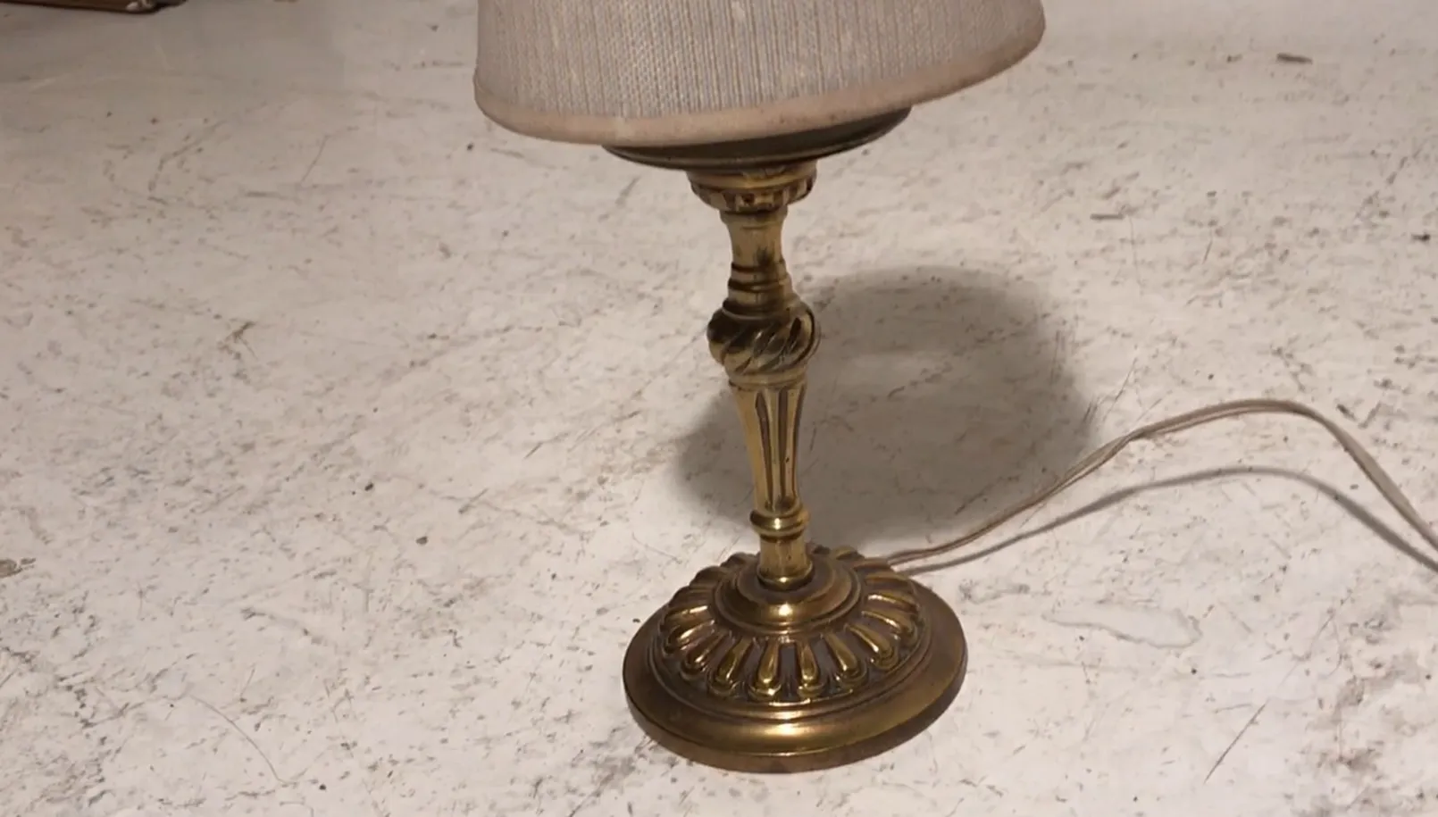 Luminária de mesa antiga com base decorativa e cúpula clara.