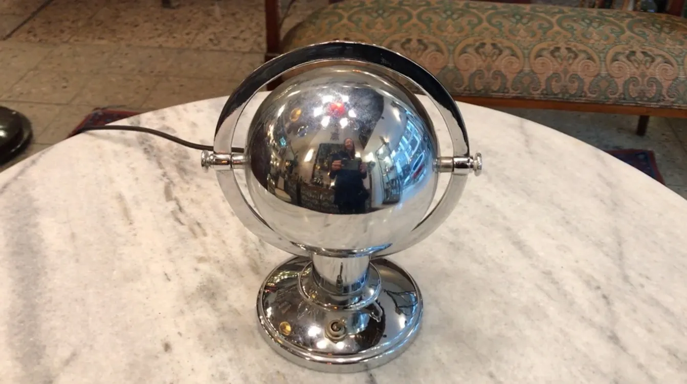 Antike Tischlampe mit glänzendem Kugeldesign in klassischer Umgebung.