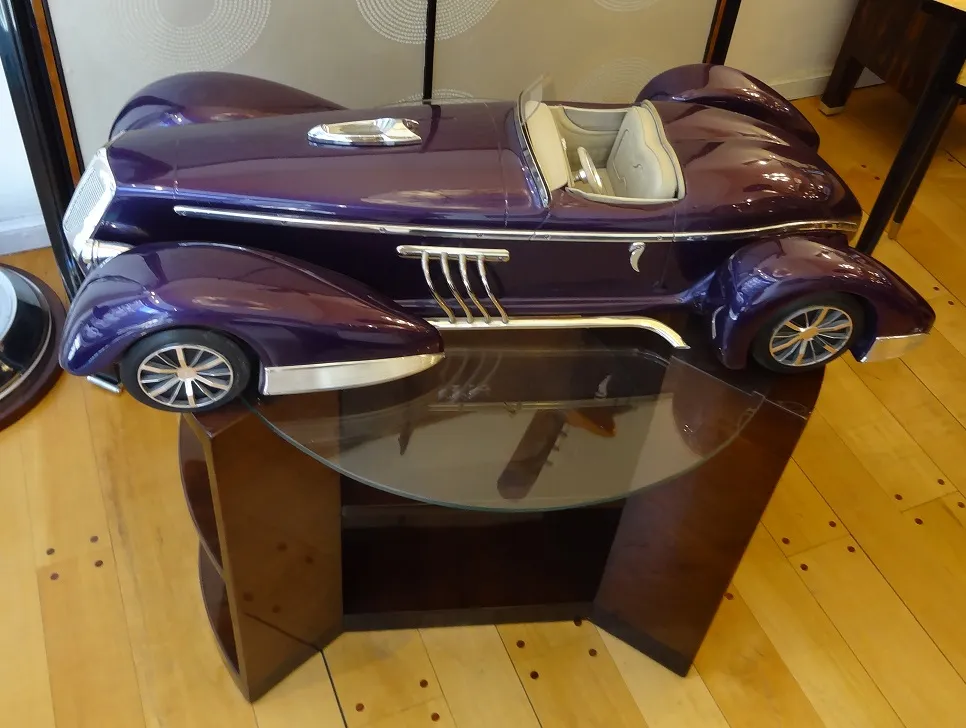 auto antiguo del diseñador Marcelo Peña, color púrpura, en una mesa de vidrio.