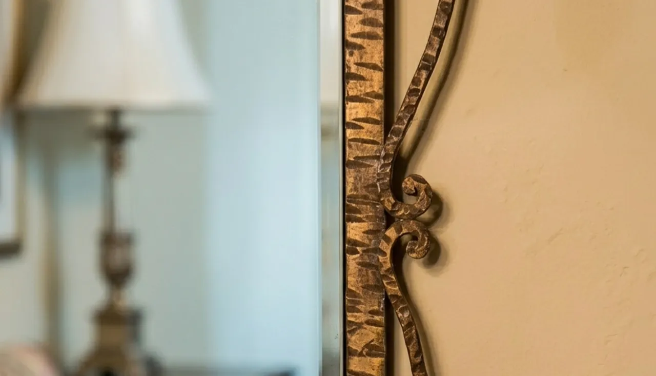 specchio antico decorativo con complesso telaio dorato, in ambiente classico con lampada