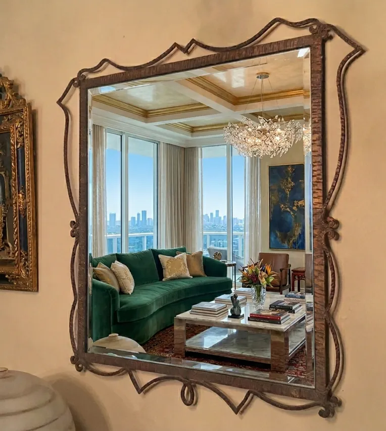 espejo antiguo con marco decorativo en una sala elegante con sofá verde