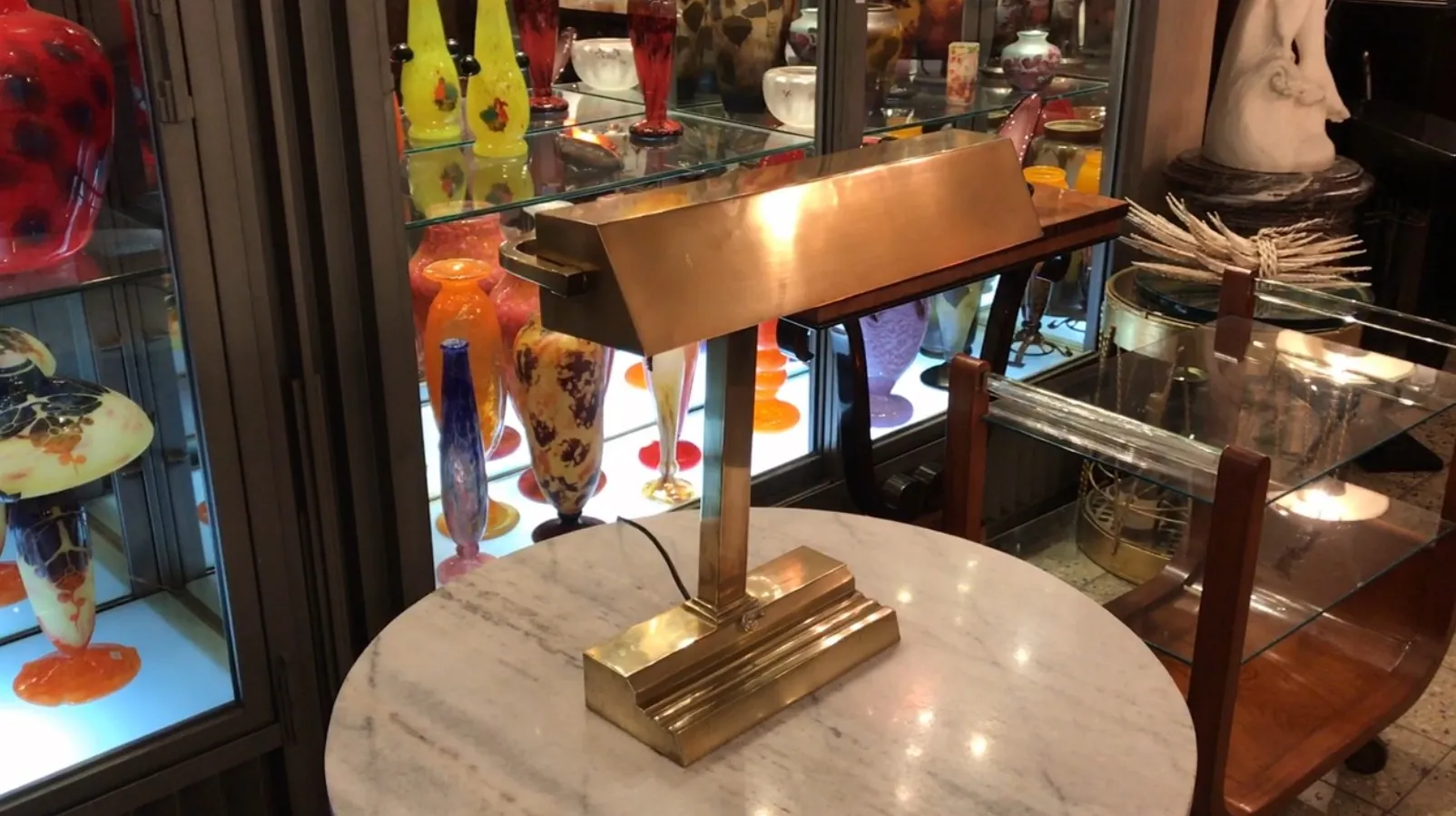 lampada da tavolo antica con design art deco, circondata da oggetti in vetro colorato