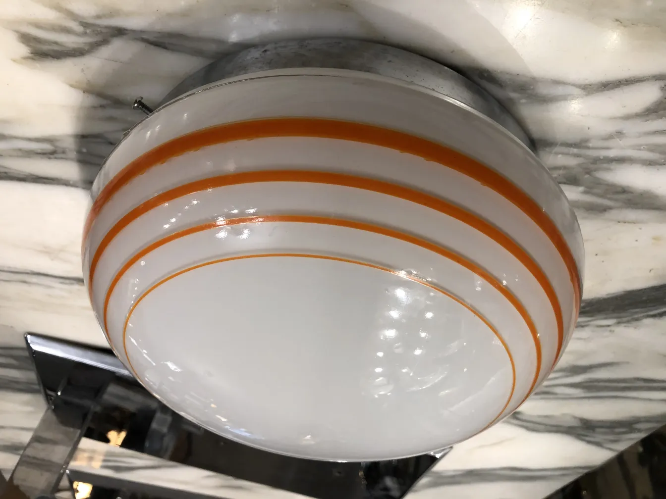 Três luzes de teto antigas com detalhes laranja, iluminando o espaço