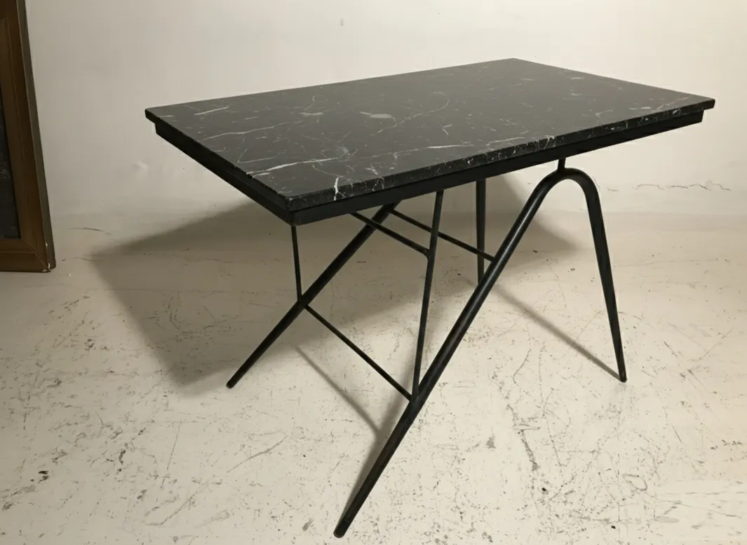 mesa antigua de jardín con superficie negra y patas metálicas