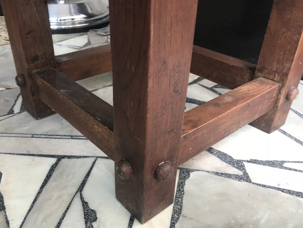 detalhe de uma mesa de centro antiga com laterais de madeira em um ambiente elegante