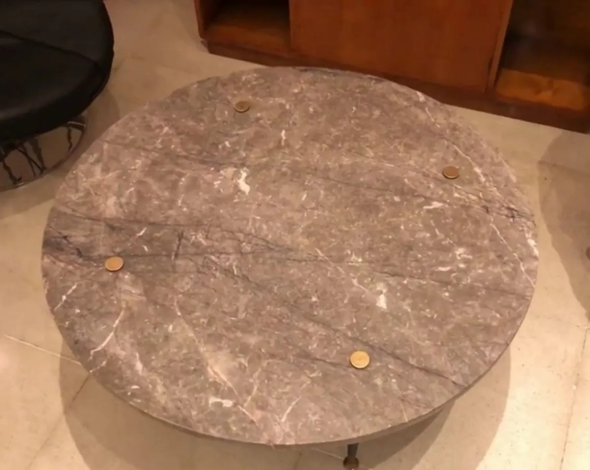 mesa de centro antiga redonda com superfície decorativa e pernas de metal, em um ambiente aconchegante