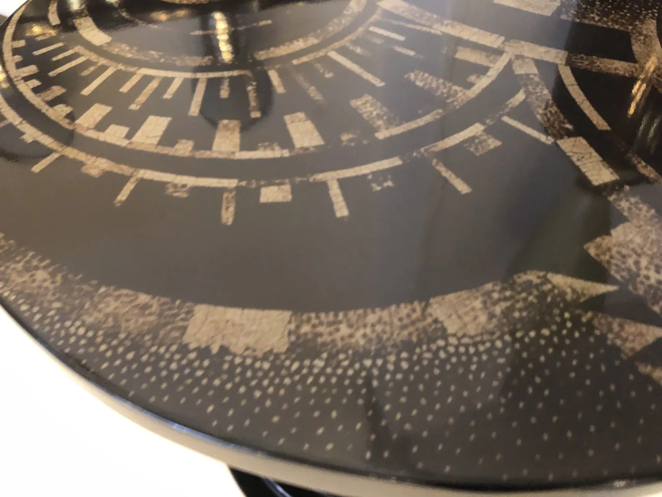 Petite table antique avec surface sombre et motifs.